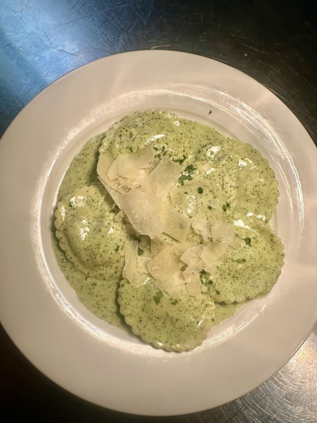 Ravioli in creamy pesto sauce with shaved parmesan